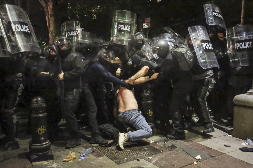 01.05.2024, Georgien, Tiflis: Bereitschaftspolizisten halten einen Demonstranten während einer Demonstration der Opposition gegen das &quot;russische Gesetz&quot; in der Nähe des Parlamentsgebäudes in ...