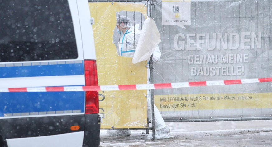 Ein Beamter der Spurensicherung geht durch einen Bauzaun zum Königsreichssaal der Zeugen Jehovas in der Straße Deelböge. Dort kam es am Donnerstagabend zu einem mutmaßlichen Amoklauf, bei dem mehrere  ...