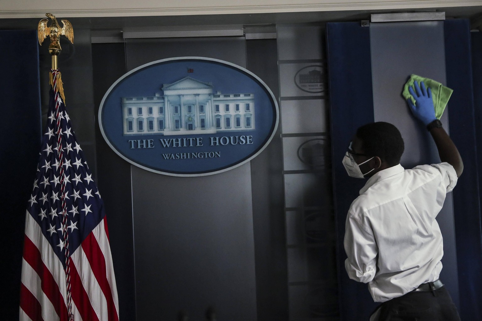 Staff clean the podium area in the James S. Brady Press Briefing Room prior to a press conference held by President Donald Trump, at the White House in Washington, D.C., U.S., on Thursday, August 13,  ...
