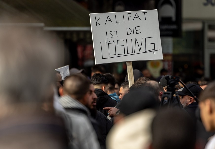 27.04.2024, Hamburg: Teilnehmer einer Islamisten-Demo halten ein Plakat mit der Aufschrift &quot;Kalifat ist die Lösung&quot; in die Höhe. Foto: Axel Heimken/dpa +++ dpa-Bildfunk +++
