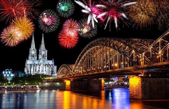 Night with fireworks in Cologne at the river Rhine with the illuminated cathedral and the Hohenzollern Bridge.