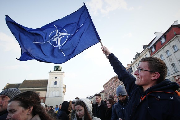 A man holds a NATO flag near the Royal Castle ahead of a speech by US president Joe Biden on March 26, 2022 in Warsaw, Poland. President Biden spent his second day in Warsaw on Saturday visiting refug ...