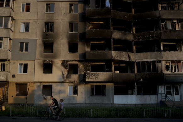 Ein Mann fährt mit dem Fahrrad vor einem durch Beschuss zerstörten Gebäude in Borodjanka am Stadtrand von Kiew. Präsident Selenskyj hat erneut betont, wie essentiell wichtig Unterstützung mit Raketenabwehr-Systemen für die Ukraine ist.  