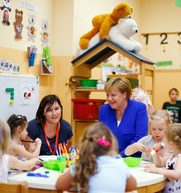 Chancellor Angela Merkel sits with kids at the Caritas Association kindergarten in Cologne, Germany, July 18, 2018. REUTERS/Thilo Schmuelgen