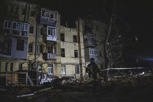 29.01.2023, Ukraine, Charkiw: Ein Rettungssanitäter geht vor einem Wohnhaus im Stadtzentrum, das von einer russischen Rakete getroffen wurde, entlang. Foto: Yevhen Titov/AP/dpa +++ dpa-Bildfunk +++