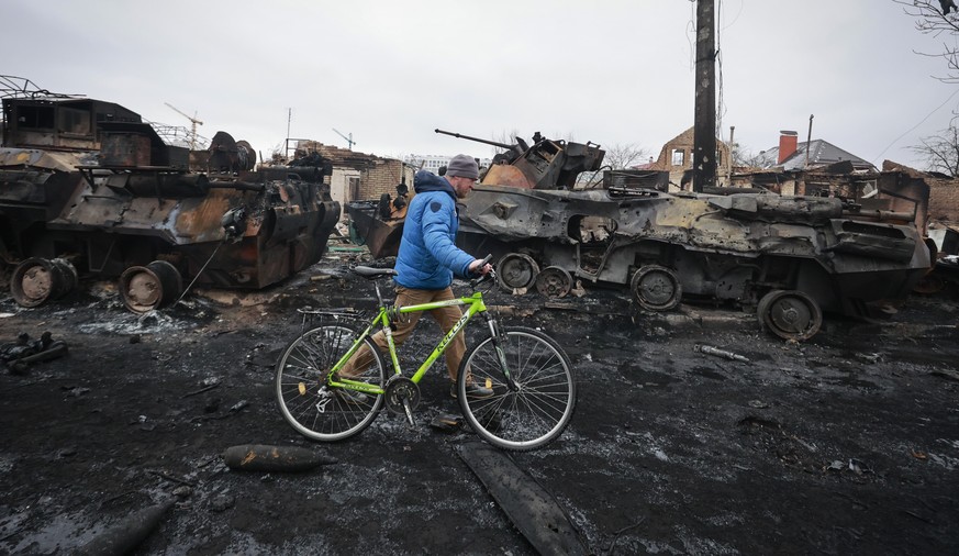 A man walks past the remains of a Russian military vehicles in Bucha, close to the capital Kyiv, Ukraine, Tuesday, March 1, 2022. Russia on Tuesday stepped up shelling of Kharkiv, Ukraine's second-lar ...