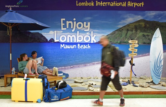 Foreign tourists sit at a photo booth as their flight to Bali was canceledled due to Mount Agung's eruption, at Lombok International airport in Lombok Tengah, Indonesia, June 29, 2018. Antara Foto/Ahm ...