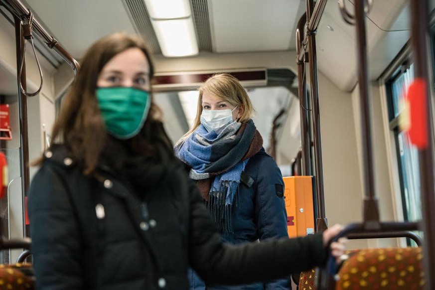 JENA, GERMANY - APRIL 03: Sophie Frick and Anne Boettner demonstrate wearing a protective face mask in a tram at a press event of the local public transport company ahead of a city ordinance that will ...