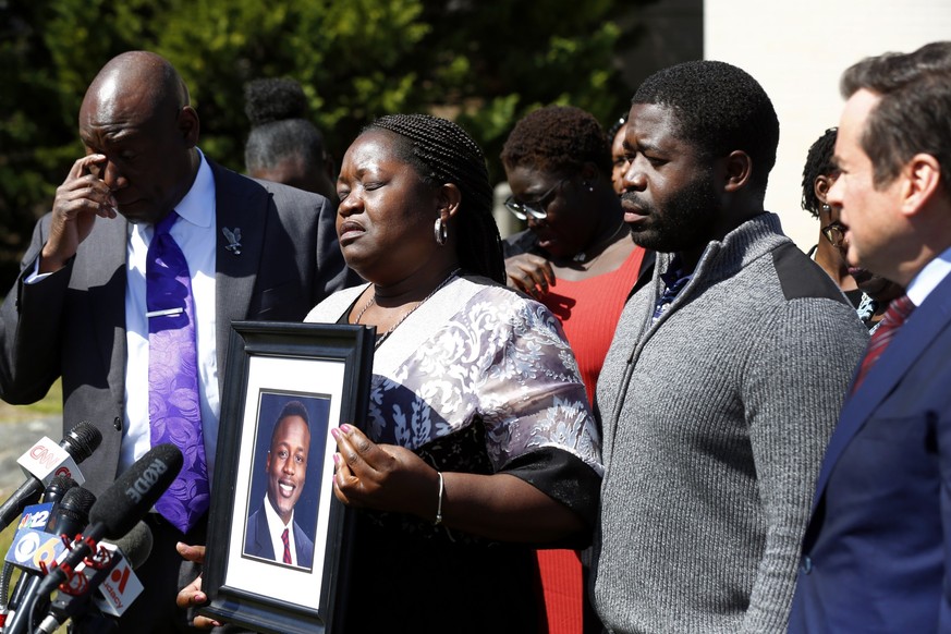 Caroline Ouko, mother of Irvo Otieno, holds a portrait of her son with attorney Ben Crump, left, her older son, Leon Ochieng and attorney Mark Krudys at the Dinwiddie Courthouse in Dinwiddie, Va., on  ...