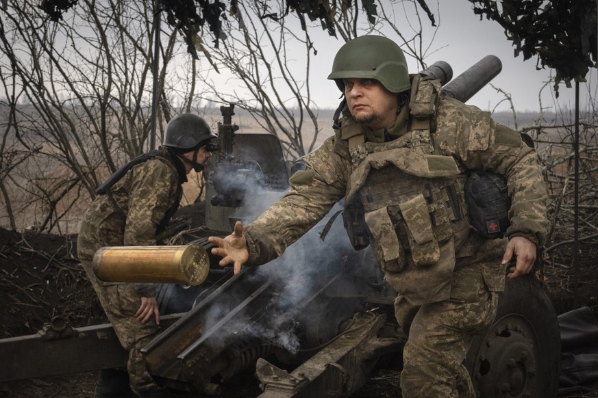 ARCHIV - 22.03.2024, Ukraine, Awdijiwka: Ukrainische Soldaten der 71. Jägerbrigade feuern eine Haubitze M101 auf russische Stellungen an der Frontlinie. (zu dpa: «Ukraine senkt Alter für Einberufung v ...