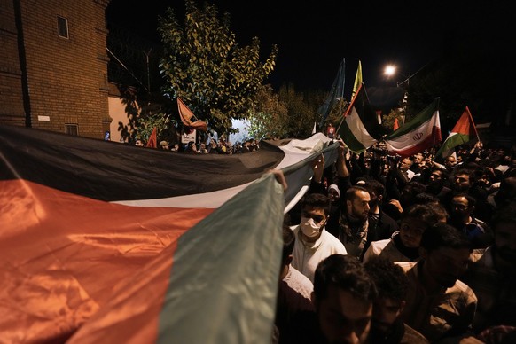18.10.2023, Iran, Teheran: Demonstranten tragen eine riesige palästinensische Flagge während einer Anti-Israel-Demonstration vor der französischen Botschaft in Teheran, Iran. Eine massive Explosion er ...