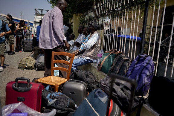 Migrants sit outside a building after being evicted by police in Rome, Thursday, July 5, 2018. Over 100 migrants, most of them refugees, were evicted from a squatted building in Rome. (AP Photo/Andrew ...