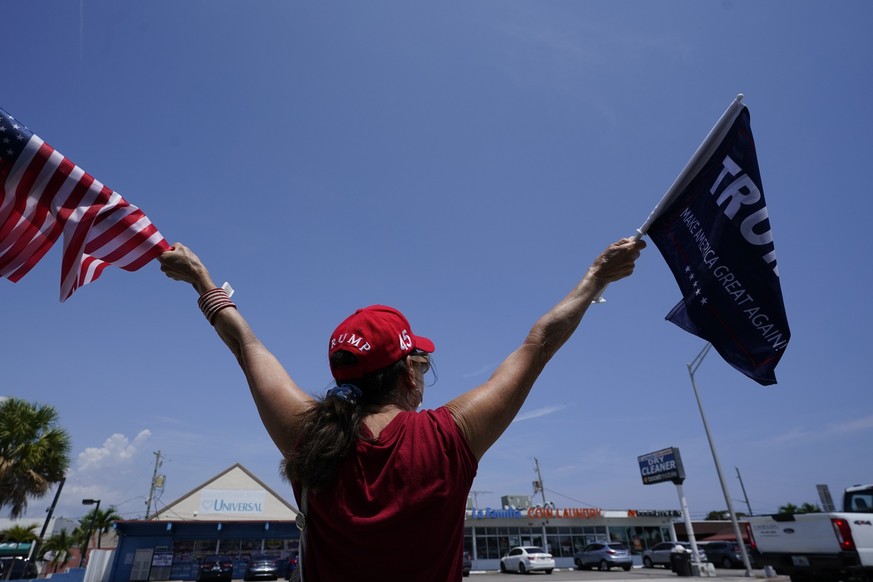 A supporter of former President Donald Trump waves flags Monday, April 3, 2023, in West Palm Beach, Fla. Trump is expected to travel to New York for his booking and arraignment on charges arising from ...
