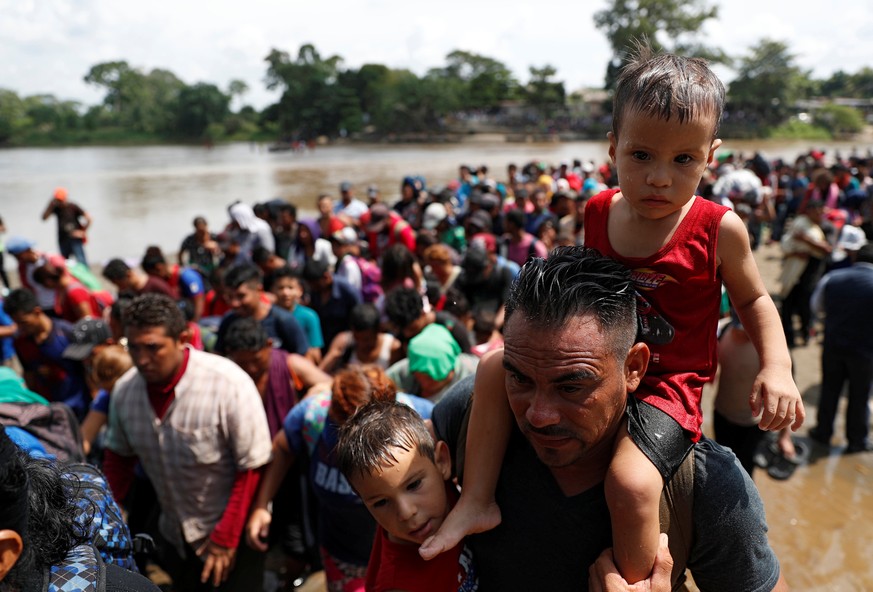 Migrants, part of a caravan traveling to the U.S., stand in line to climb a little hill after crossing the Suchiate river, a natural border between Guatemala and Mexico, in Ciudad Hidalgo, Mexico Octo ...