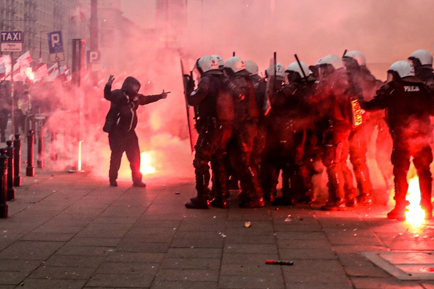 11.11.2020, Polen, Warschau: Ein Teilnehmer des Unabhängigkeitsmarschs steht vor einer Gruppe Polizisten. Trotz eines Verbots sind Tausende polnische Nationalisten und Rechtsradikale durch die Stadt g ...