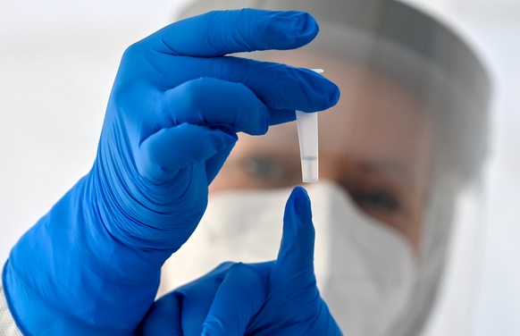Ein Mitarbeiterin zeigt ein Röhrchen mit der Trägerflüssigkeit für einen Corona-Schnelltest.