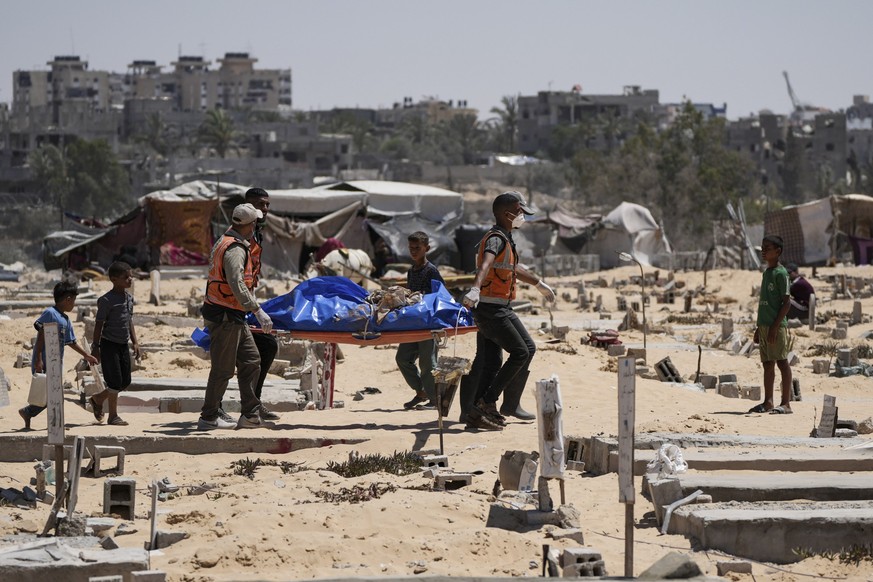 FILE - Workers carry a body, one of more than 80 bodies returned by Israel, to a cemetery in Khan Younis, Gaza Strip, Monday, Aug. 5, 2024. (AP Photo/Abdel Kareem Hana, File)