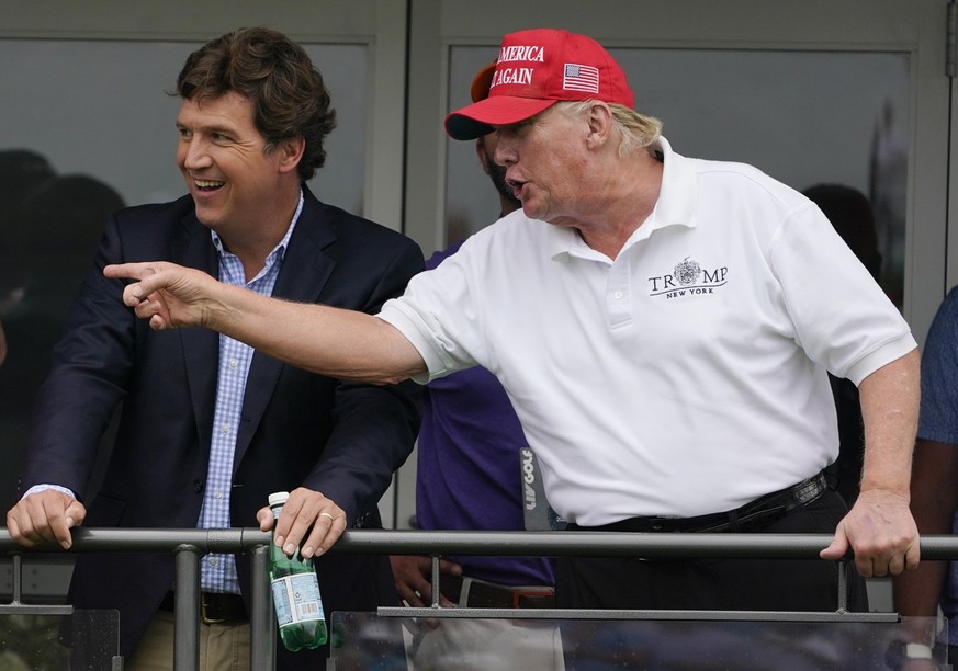 Rep. Marjorie Taylor Greene, left, R-Ga.; political commentator Tucker Carlson, center; and former President Donald Trump talk while watching golfers on the 16th tee during the final round of the LIV  ...