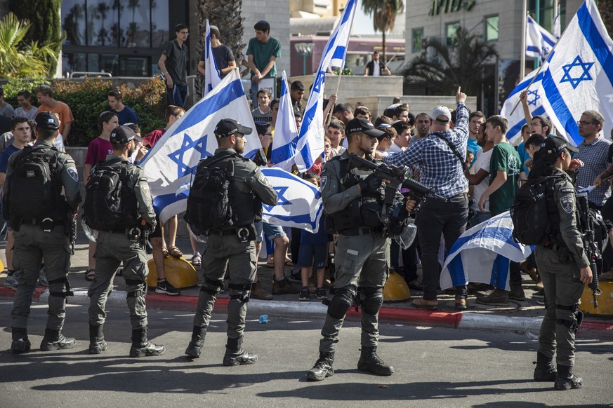 Israelische Grenzpolizisten schieben Wache, während jüdische rechte Demonstranten die Freilassung von drei Juden fordern, die wegen der Ermordung von eines arabischen Israelis verhaftet wurden.