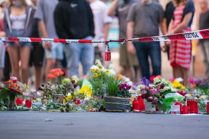 Trauerkerzen und Blumen liegen vor einem Kaufhaus in der Innenstadt, in dem ein Mann Menschen mit einem Messer attackiert hatte. Bei dem Angriff am 25.06.2021 hatte ein Somalier drei Frauen in einem K ...