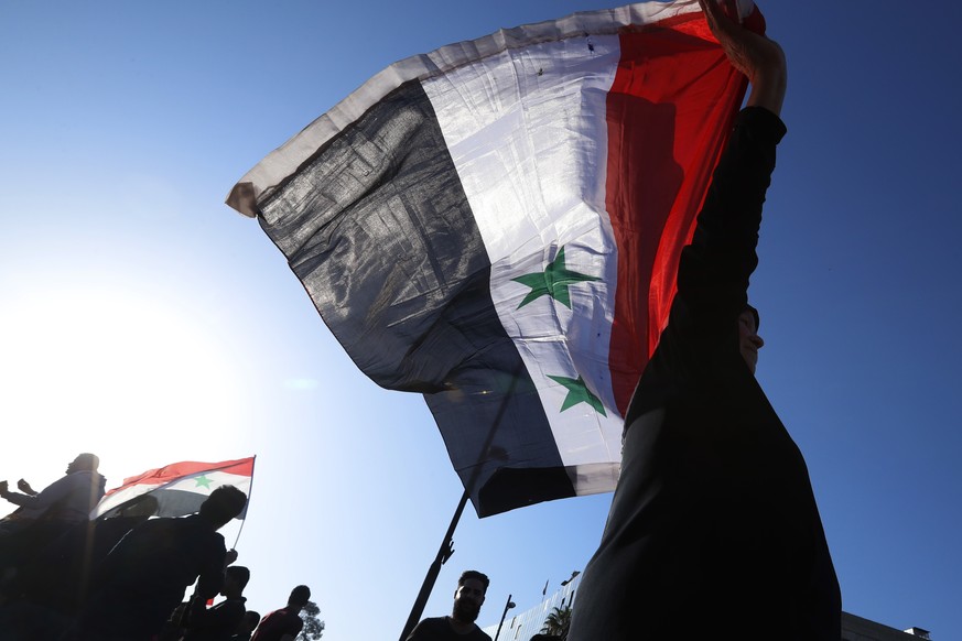 A Syrian government supporter holds up a Syrian national flag as he chants slogans against U.S. President Trump during demonstrations following a wave of U.S., British and French military strikes to p ...