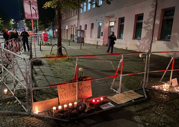 18.10.2023, Berlin: Brennende Kerzen stehen vor Schildern mit der Aufschrift