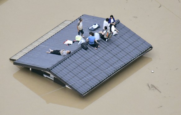 An aerial view shows local residents seen on the roof of submerged house at a flooded area as they wait for a rescue in Kurashiki, southern Japan, in this photo taken by Kyodo July 7, 2018. Mandatory  ...