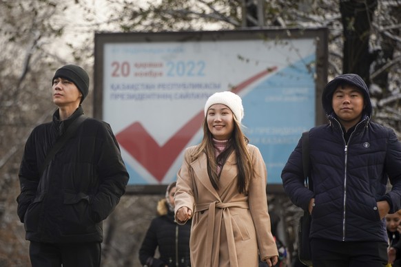 Kazakh youth walk down a street with an election poster in the background in Almaty, Kazakhstan, Thursday, Nov. 17, 2022. Kazakhstan&#039;s president, who faced a bloody outburst of unrest early this  ...