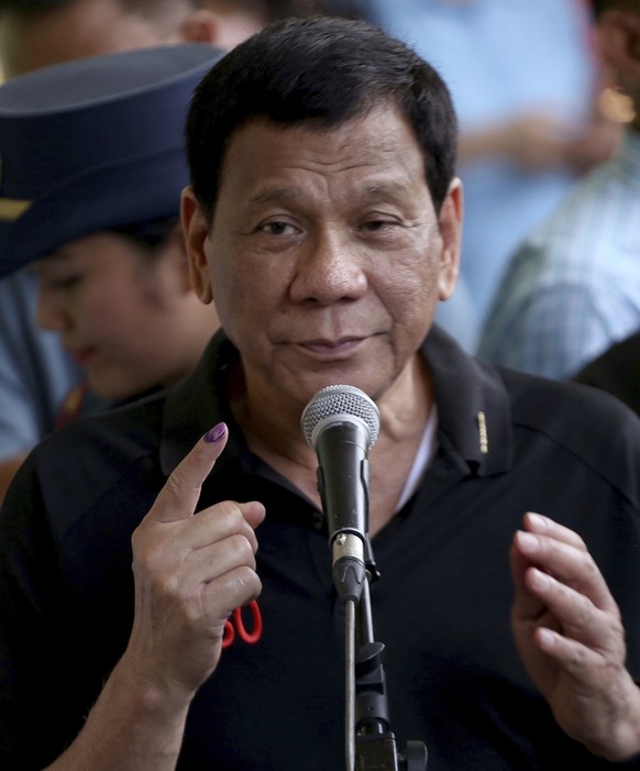 President Rodrigo Duterte shows his forefinger with an indelible ink to prove that he has voted for the country's midterm elections in his hometown of Davao city in southern Philippines Monday, May 13 ...