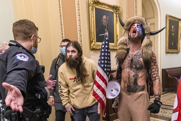 FILE - In this Wednesday, Jan. 6, 2021 file photo, supporters of President Donald Trump, including Jacob Chansley, right with fur hat, are confronted by U.S. Capitol Police officers outside the Senate ...