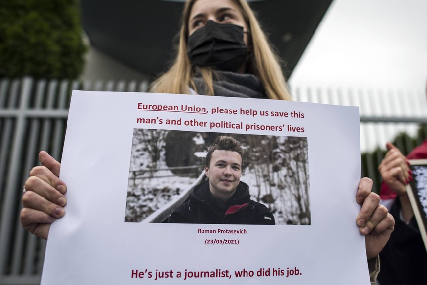 Eine belarussische Demonstrantin im Exil in Polen hält ein Plakat, das den verhafteten Journalisten Roman Protasewitsch zeigt.