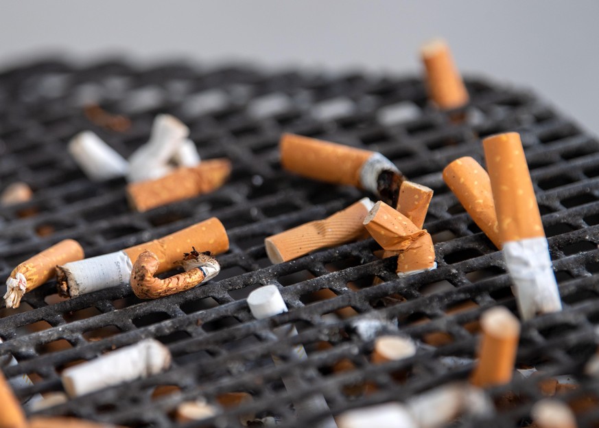 ARCHIV - 07.10.2019, Brandenburg, Potsdam: Zahlreiche Zigarettenstummel liegen in einem Aschenbecher vor einem B