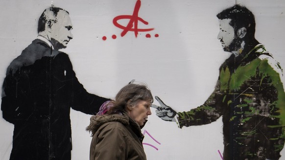 04.05.2023, Großbritannien, London: Eine Frau geht an einem Graffiti vorbei, das den ukrainischen Präsidenten Selenskyj (r) und den russischen Präsidenten Putin darstellt. Foto: Vadim Ghirda/AP/dpa ++ ...