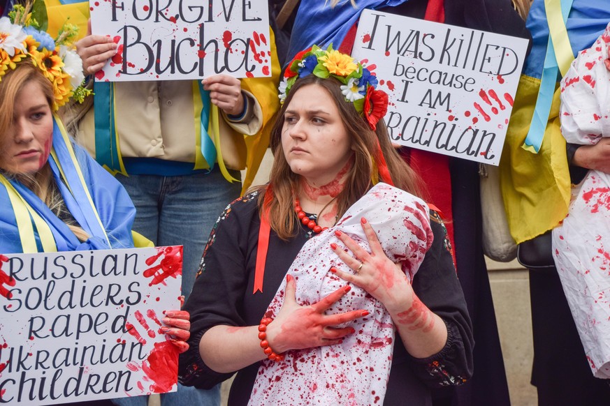 April 9, 2022, London, England, United Kingdom: Demonstrators staged a massive &#039;die-in&#039; and held &#039;babies&#039; and signs covered in fake blood in protest against the massacre in the tow ...