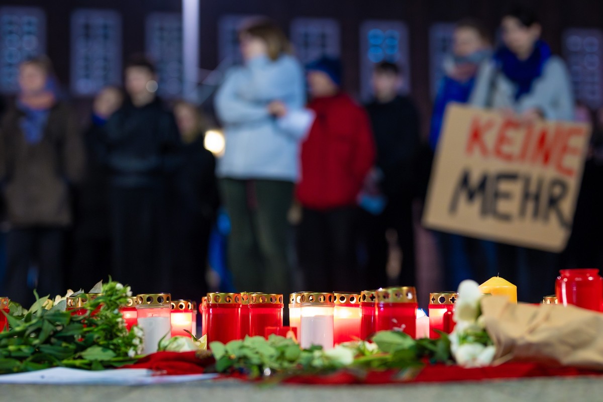 ARCHIV - 15.11.2023, Niedersachsen, Hannover: Menschen nehmen an einer Demonstration gegen Femizide auf dem Goseriedeplatz in Hannover teil und stehen dabei hinter niedergelegten Blumen und Kerzen. (z ...