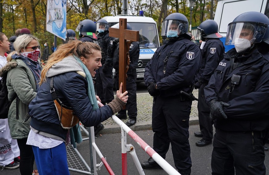 BERLIN, GERMANY - NOVEMBER 18: A woman holding a crucifix screams at riot police during protests next to the Reichstag against modifications to a law called the &quot;infection protection law&quot; (& ...