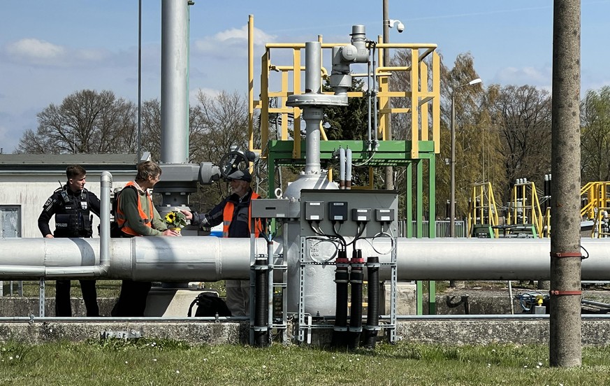 Aktivisten stehen in der Pumpstation neben einem Polizisten. Bei einer Protestaktionen der Gruppe &quot;Letzte Generation&quot; gegen Ölimporte haben Klimaschützer versucht, die Versorgung über die Ro ...