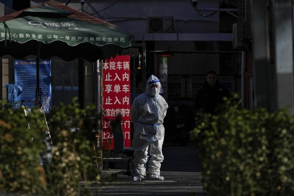 Ein Sicherheitsbeamter in Schutzkleidung steht an einem Eingangstor zu einem Wohnviertel in Peking Wache.