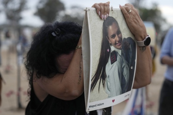 dpatopbilder - 07.10.2024, Israel, Kibbuz Reim: Eine Frau lehnt an einem Bild von Mapal Adam am Ort des Nova-Musikfestivals, bei dem Hunderte von Feiernden getötet und von der Hamas entführt und in de ...