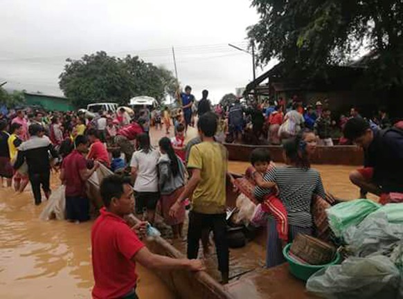 In this Tuesday, July 24, 2018, image from video, people are evacuated through the floodwaters from a collapsed dam in southeastern Laos. Rescue efforts are ongoing in villages flooded after part of a ...