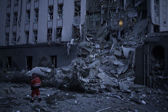 An emergency worker walks in front of a damaged hotel following a Russian attack in Kyiv, Ukraine, Saturday, Dec. 31, 2022. (AP Photo/Felipe Dana)