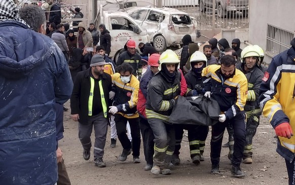 dpatopbilder - 06.02.2023, Türkei, Diyarbakir: Feuerwehrleute tragen die Leiche eines Opfers. Ein verheerendes Erdbeben hat in der Türkei und in Syrien mehr als 600 Menschen das Leben gekostet. Es gab ...