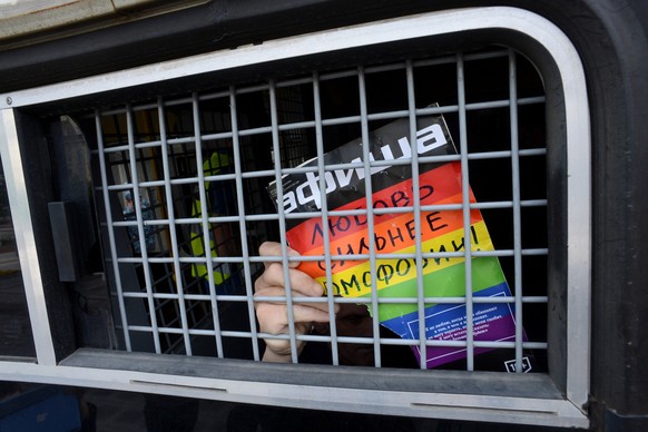A Russian gay and LGBT rights activist shows sign reading &quot;Love is stronger than homophobia&quot; from inside of a Russian riot police van during unauthorized gay rights activists rally in cental ...