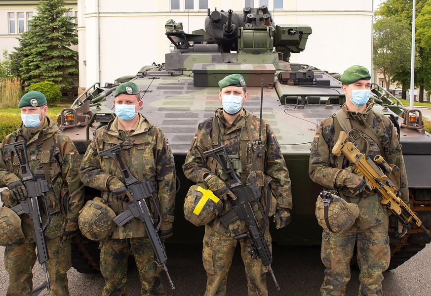 Soldiers of the German Federal Armed Forces Bundeswehr wear face maks in front of a Marder infantry tank as they attend a press presentation showing the battlefield management system (BMS) in the 37th ...