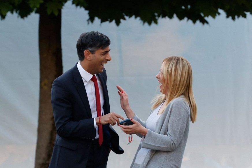 TOPSHOT - Britain&#039;s Prime Minister Rishi Sunak (L) and Italy&#039;s Prime Minister Giorgia Meloni react ahead of the social dinner during the NATO summit, at the Presidential Palace in Vilnius on ...