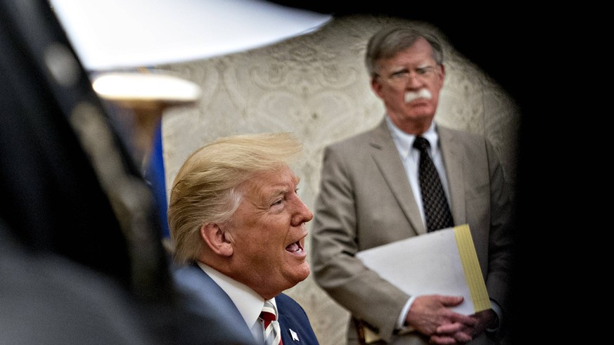 U.S. President Donald Trump, left, speaks as John Bolton, national security adviser, listens during a meeting with Klaus Iohannis, Romania s president, not pictured, in the Oval Office of the White Ho ...