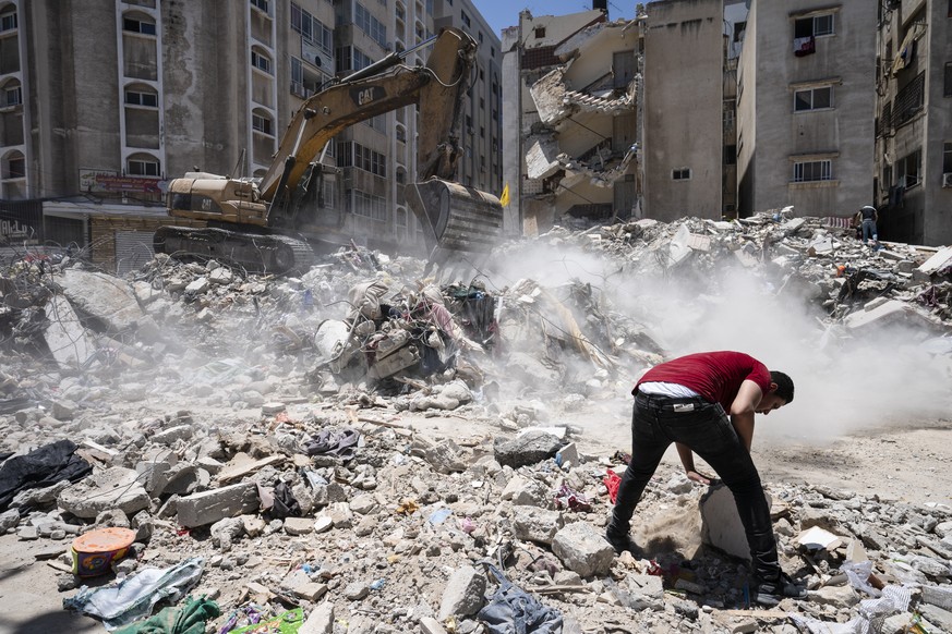 Gaza-Stadt: Menschen suchen mithilfe von Baugeräten nach Wertgegenständen in den Trümmern eines Gebäudes, das bei einem Luftangriff vor der vereinbarten Waffenruhe mit Israel zerstört wurde.