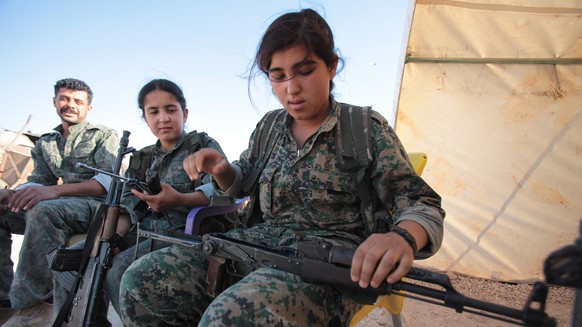 KOBANE, SYRIA - JUNE 20: (TURKEY OUT) A Kurdish People&#039;s Protection Units, or YPG&#039;s woman fighter controls her AK-47 in a camp at the outskirts of the destroyed Syrian town of Kobane, also k ...