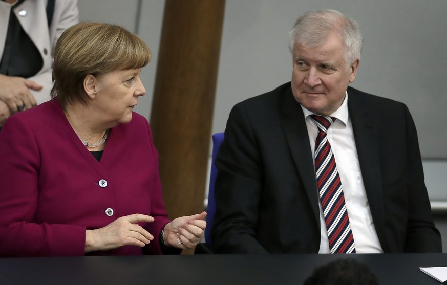 German Chancellor Angela Merkel, left, and German Interior Minister Horst Seehofer, right, talk during a meeting of the German federal parliament, Bundestag, at the Reichstag building in Berlin, Germa ...
