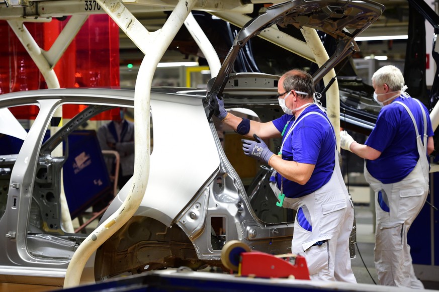 WOLFSBURG, GERMANY - APRIL 27: Workers wear face masks while working on the car assembly line on the first day of the resumption of automobile production at the Volkswagen factory during the coronavir ...